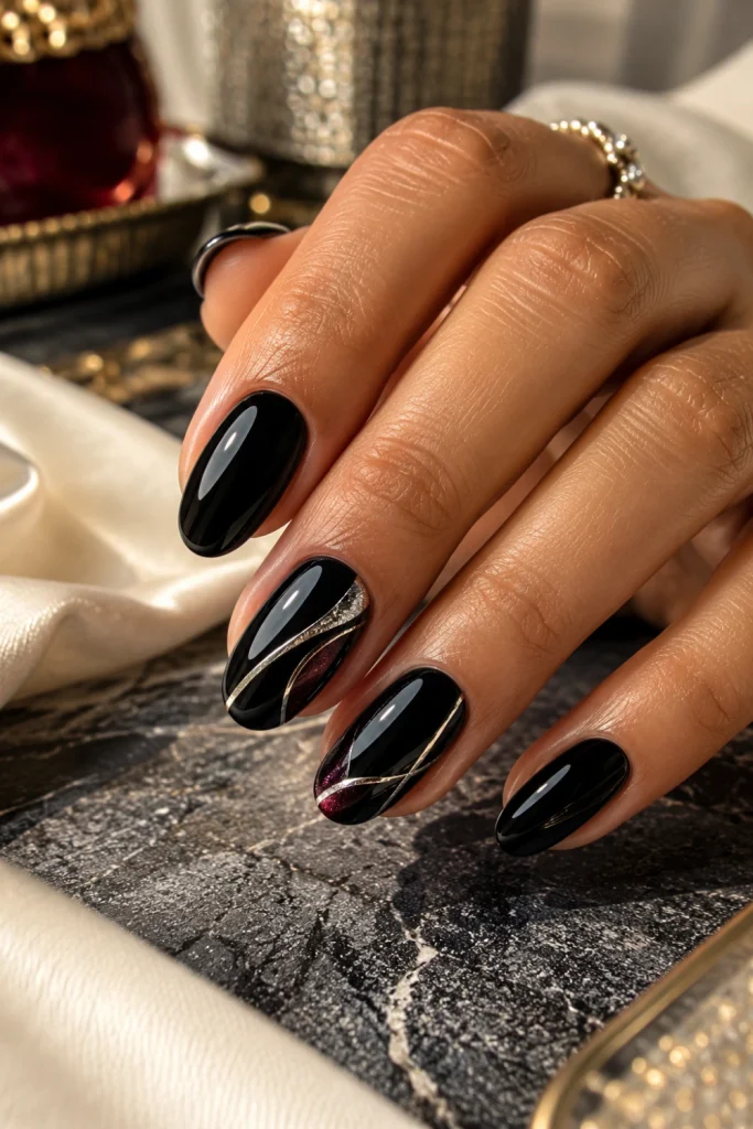 Black nail art featuring glossy black polish on short almond nails with fine silver accent lines and a contemporary finish.
